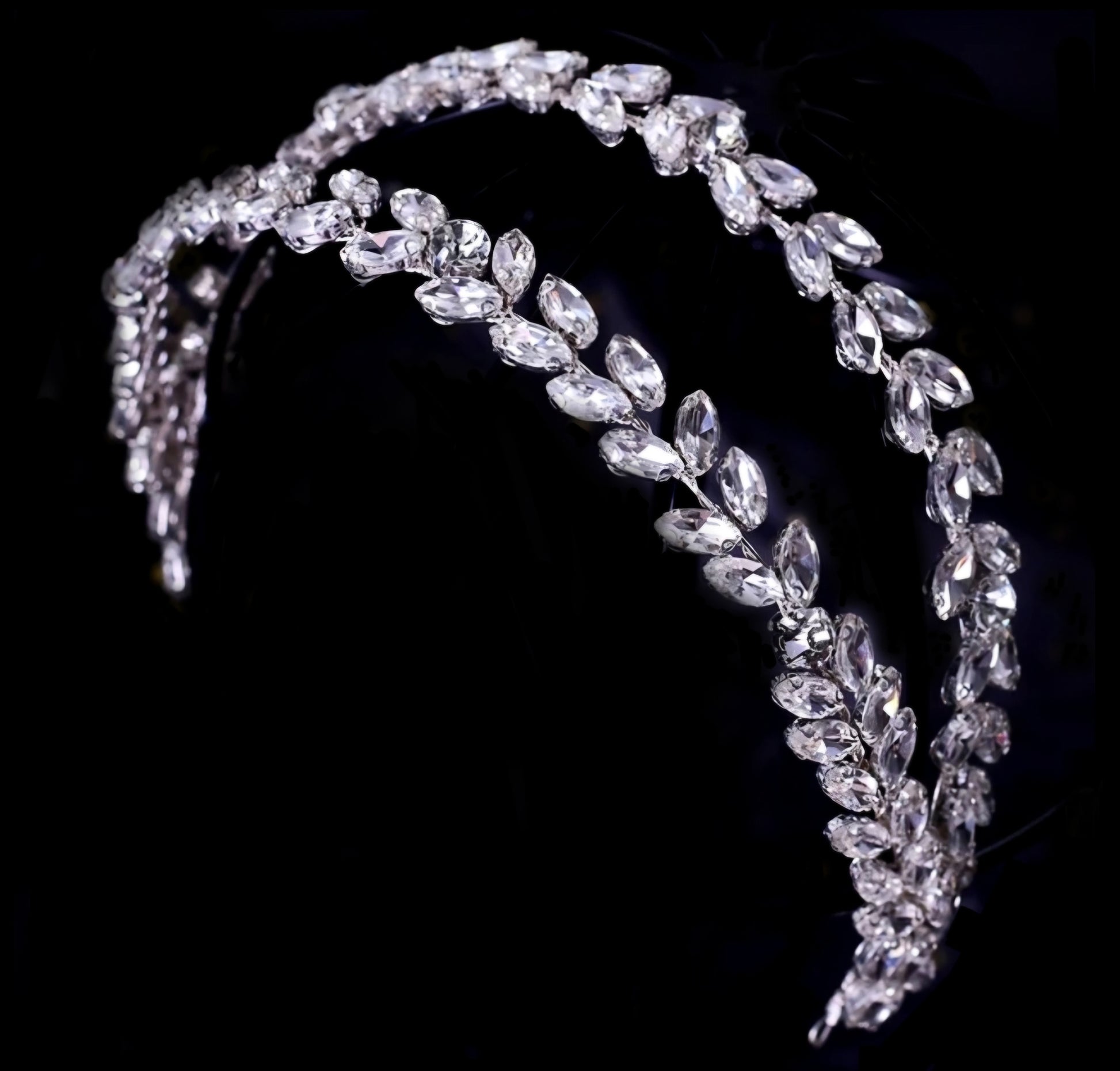 A sophisticated double-row headband featuring leaf-shaped marquise crystals in a repeating pattern, set against a deep black background for a luxury fashion campaign feel.