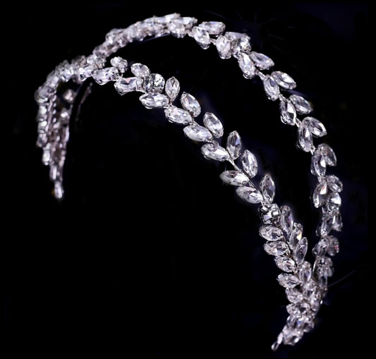 A sophisticated double-row headband featuring leaf-shaped marquise crystals in a repeating pattern, set against a deep black background for a luxury fashion campaign feel.