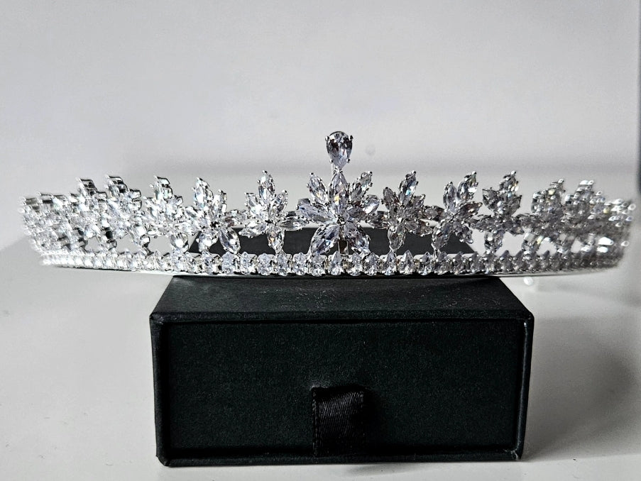 A high-end bridal tiara featuring an intricate floral starburst design crafted with brilliant-cut crystals, displayed on a premium black velvet jewelry box.