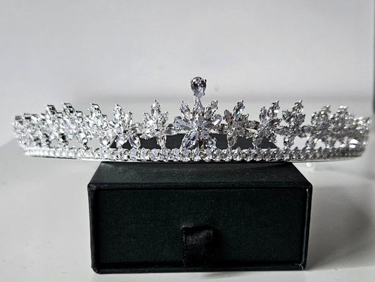 A high-end bridal tiara featuring an intricate floral starburst design crafted with brilliant-cut crystals, displayed on a premium black velvet jewelry box.