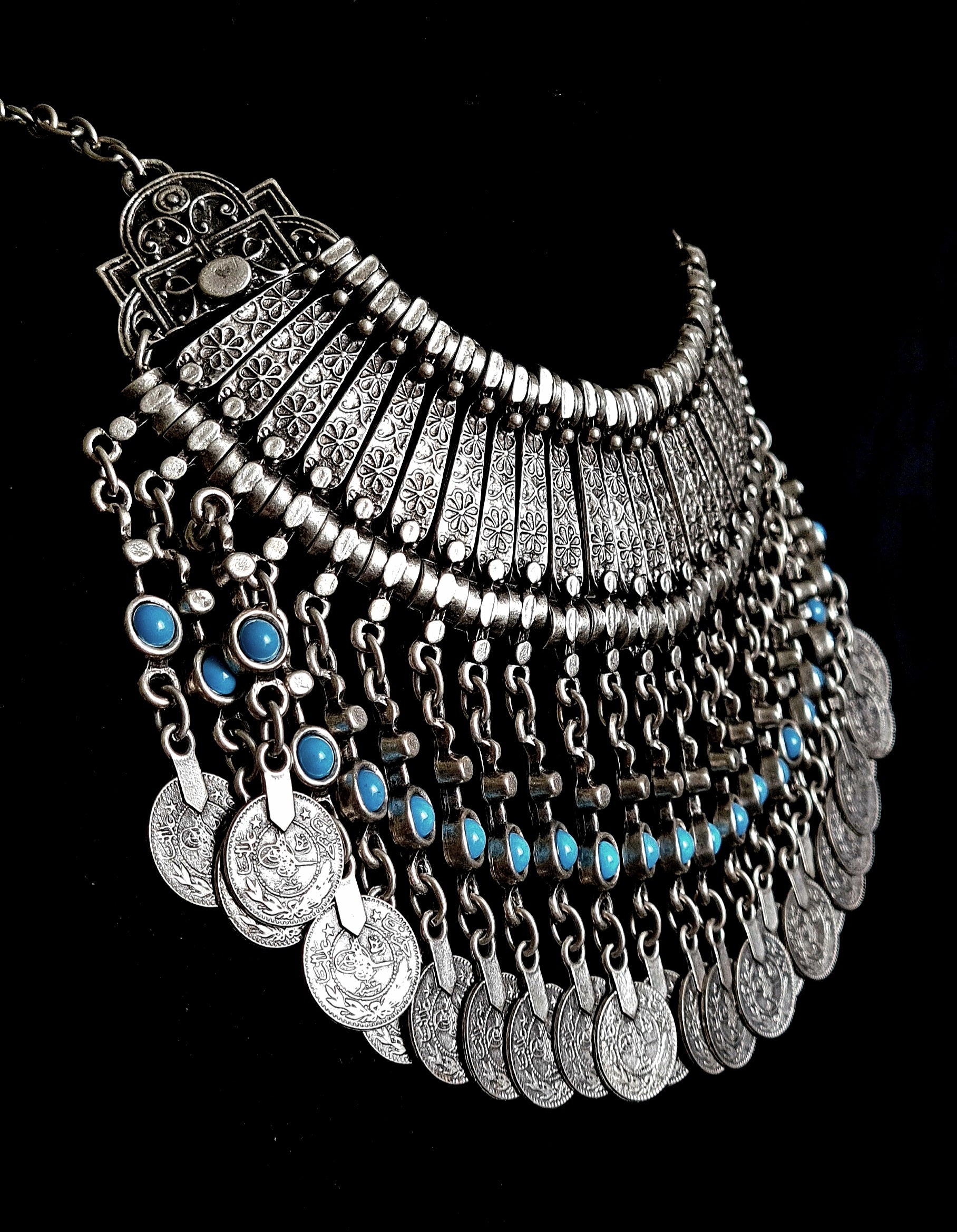 Side shot photography of the Priscilla filigree necklace showcasing meticulous metalwork, floral engravings, and vibrant turquoise cabochons on a black velvet background.