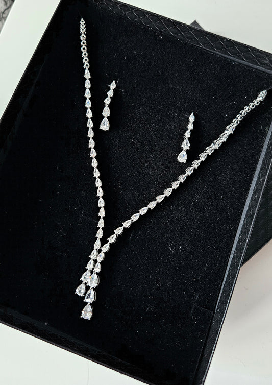 The Dilara Jewelry Set by La Pasión displayed on black box. This silver ensemble features a 44.45 cm botanical vine necklace with a 3.81 cm pear-cut drop and matching 3.18 cm x 0.64 cm marquise earrings, highlighting the brilliant craftsmanship and premium finish.