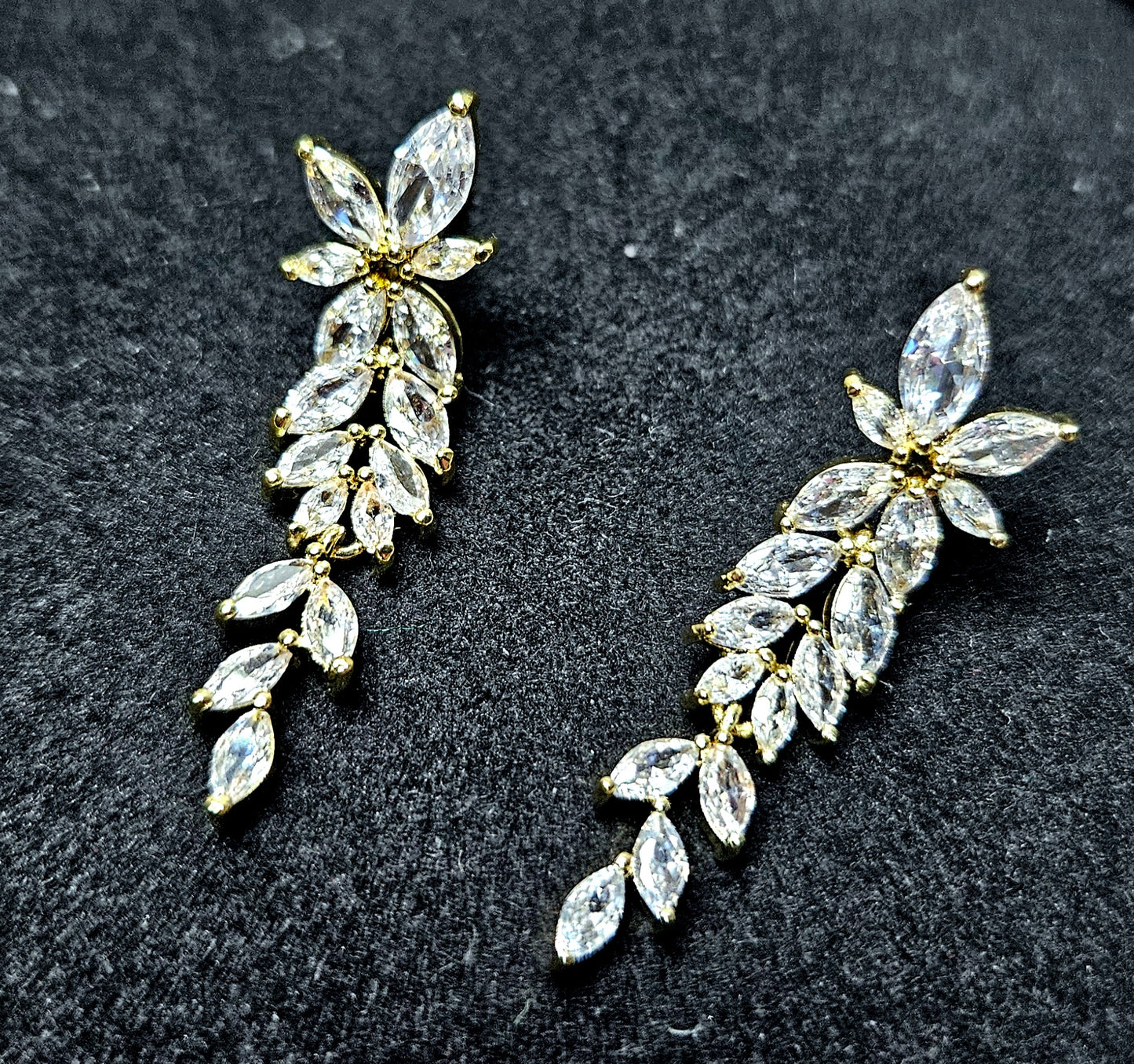 Macro photography of the La Pasión Regal Gold Earrings. The marquise stones are arranged in a botanical spray, reflecting light with exceptional clarity. Perfect for high-end social media marketing and web catalogs.