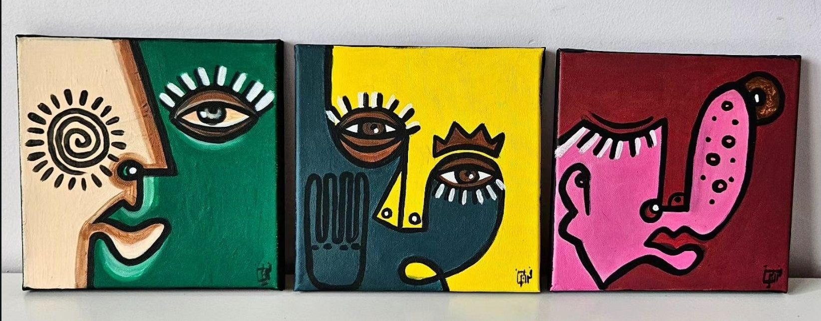  Three abstract paintings with stylized faces in different colors and shapes.