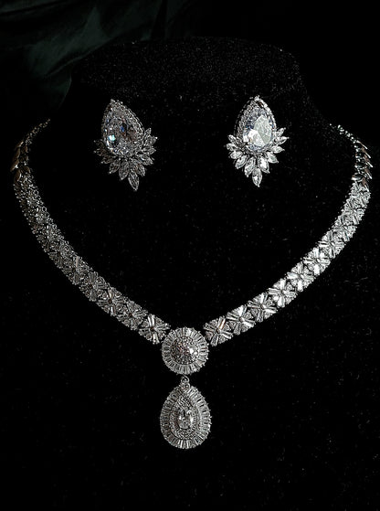 A luxury bridal jewelry set featuring a wide, intricate diamond-encrusted choker necklace with a large pear-shaped drop pendant and matching teardrop halo earrings, displayed against a premium black velvet background.