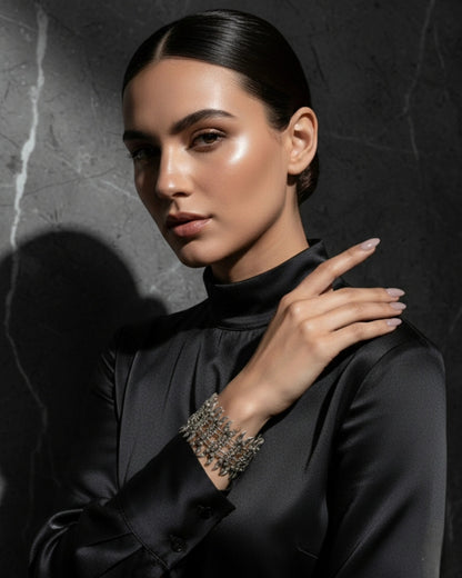 Premium fashion campaign image of a model showcasing an intricate silver spike cuff bracelet, featuring high-contrast lighting that emphasizes the metallic texture and sophisticated styling.