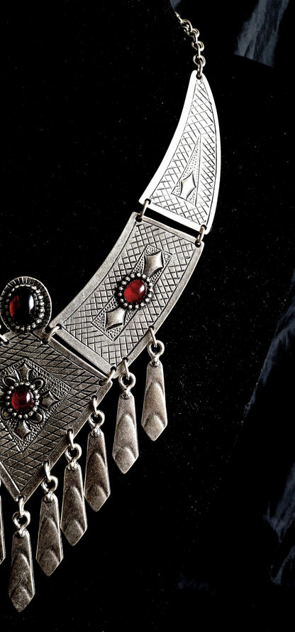 High-fashion mid-length editorial portrait of a model in a sophisticated black gown wearing the artisan tribal silver necklace with red stones, captured in a premium, flagship brand style.