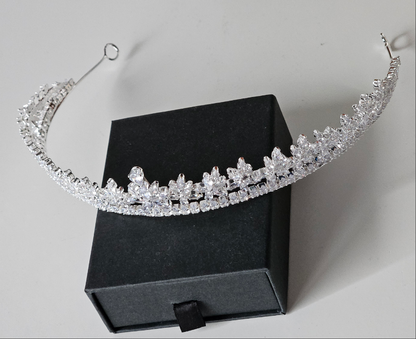 An editorial-style angled shot of a silver-toned wedding tiara with marquise-cut crystal clusters, highlighting the delicate craftsmanship of the high-status headpiece.
