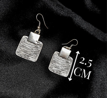 Product specification shot of square silver earrings on a black background with minimalist white lines indicating the height 