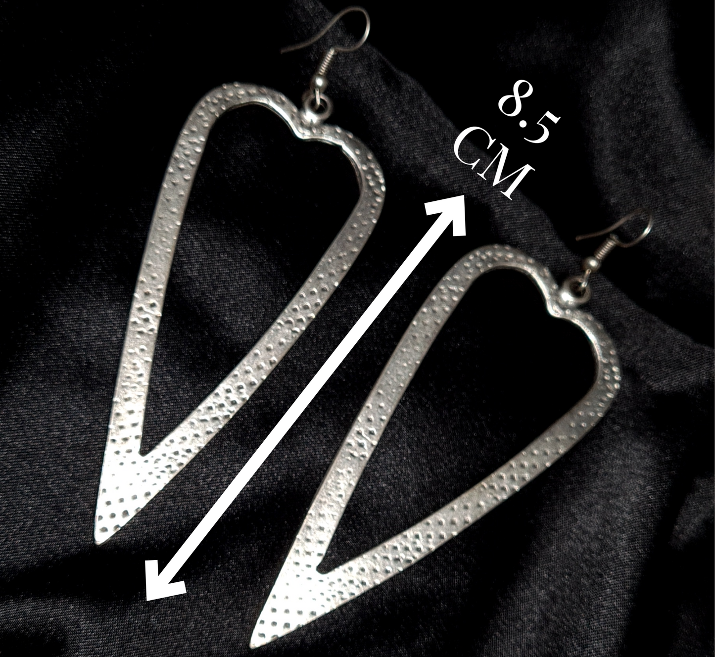 Technical specification layout of silver heart earrings on a black background, with minimalist white lines indicating the 8.5cm drop length.