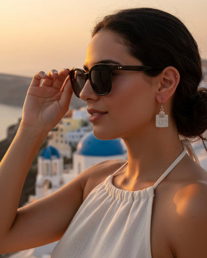 Profile portrait of a high-fashion model wearing square textured sterling silver earrings and dark sunglasses, captured in golden hour lighting with an elegant, aspirational aesthetic.