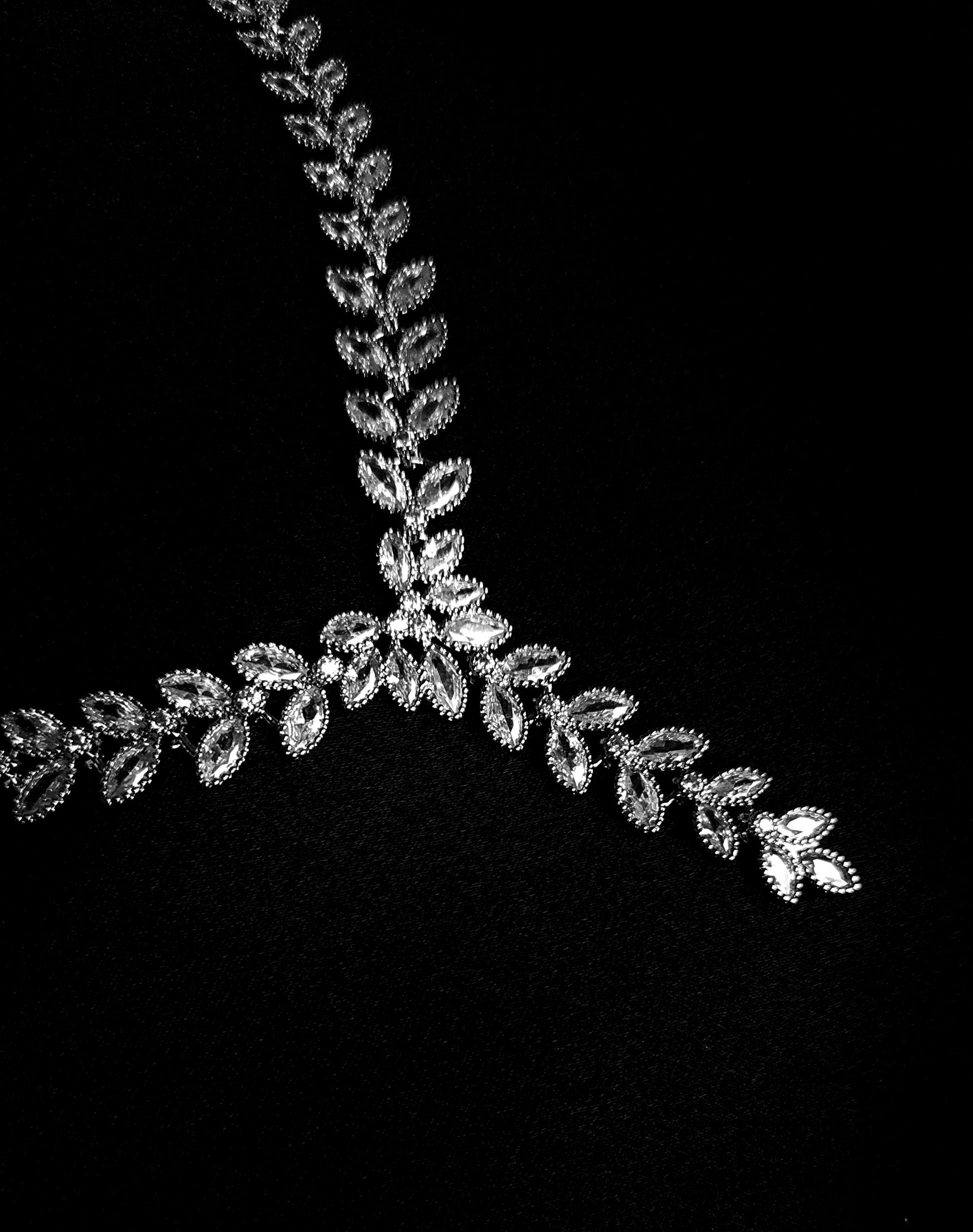 a close-up view of a silver necklace sparkling with zirconia Diamonds displayed on a black background