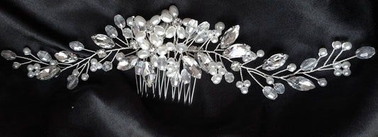 A wedding hair accessory made of silver and rhinestones. The comb is decorated with crystals and has a delicate design. The comb is perfect for a special occasion.