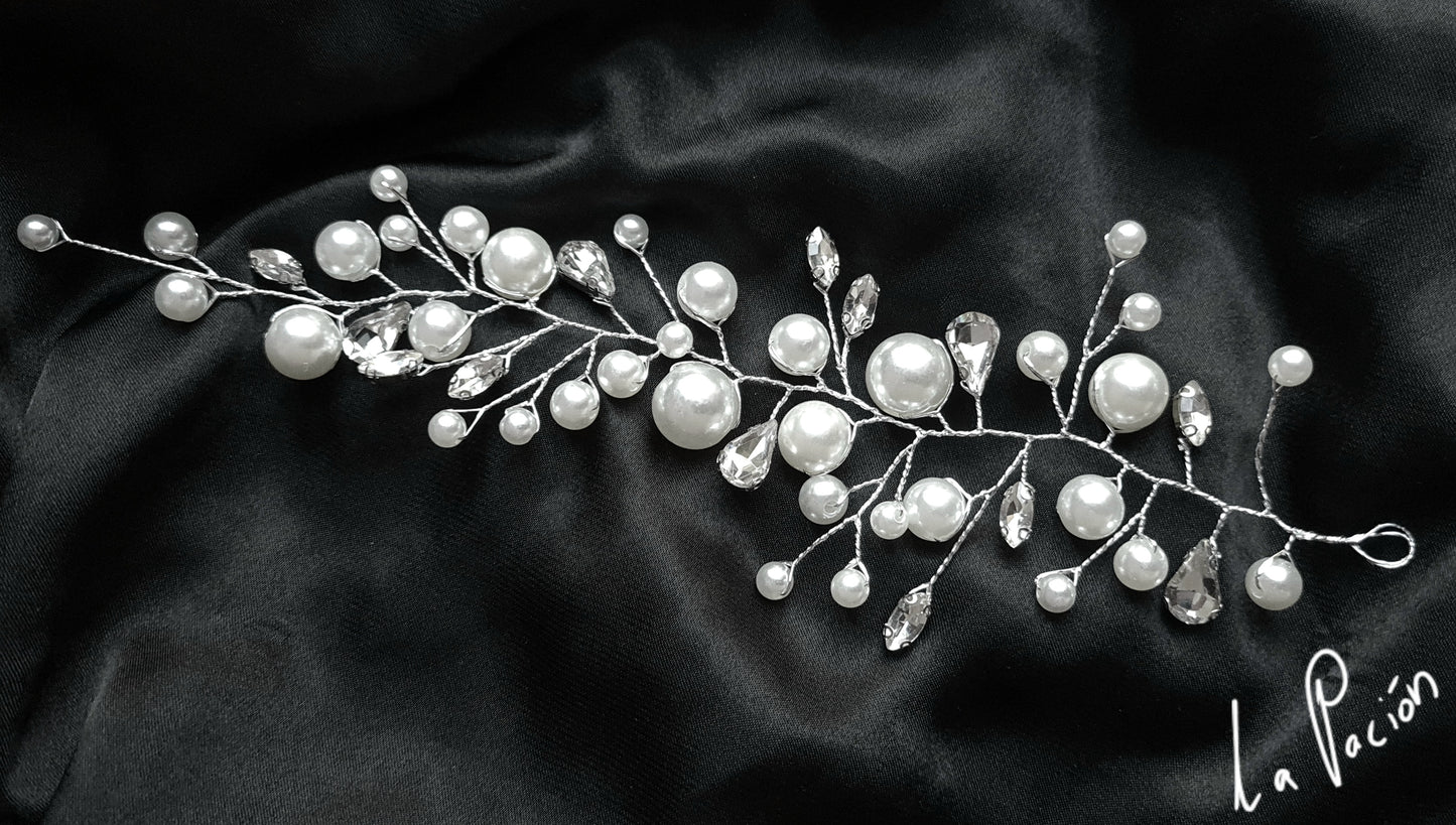 a pearl bridal hair comb on a black background. The hair comb is made of pearls and crystals, and it has a delicate, feminine design. It is perfect for a bride who wants to add a touch of elegance to her wedding day look.