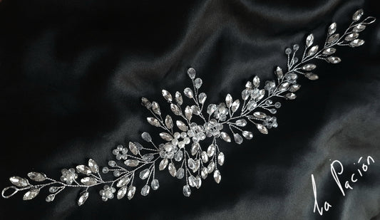 a bridal hair piece with pearls and crystals on a black background. The hair piece is made of pearls and crystals, and it has a delicate, feminine design. It is perfect for a bride who wants to add a touch of elegance to her wedding day look