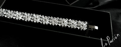  A bracelet with diamonds in a box on a black background. The bracelet is made of silver and has diamonds encrusted on it. The diamonds are sparkling and the bracelet is very shiny. The box is black.