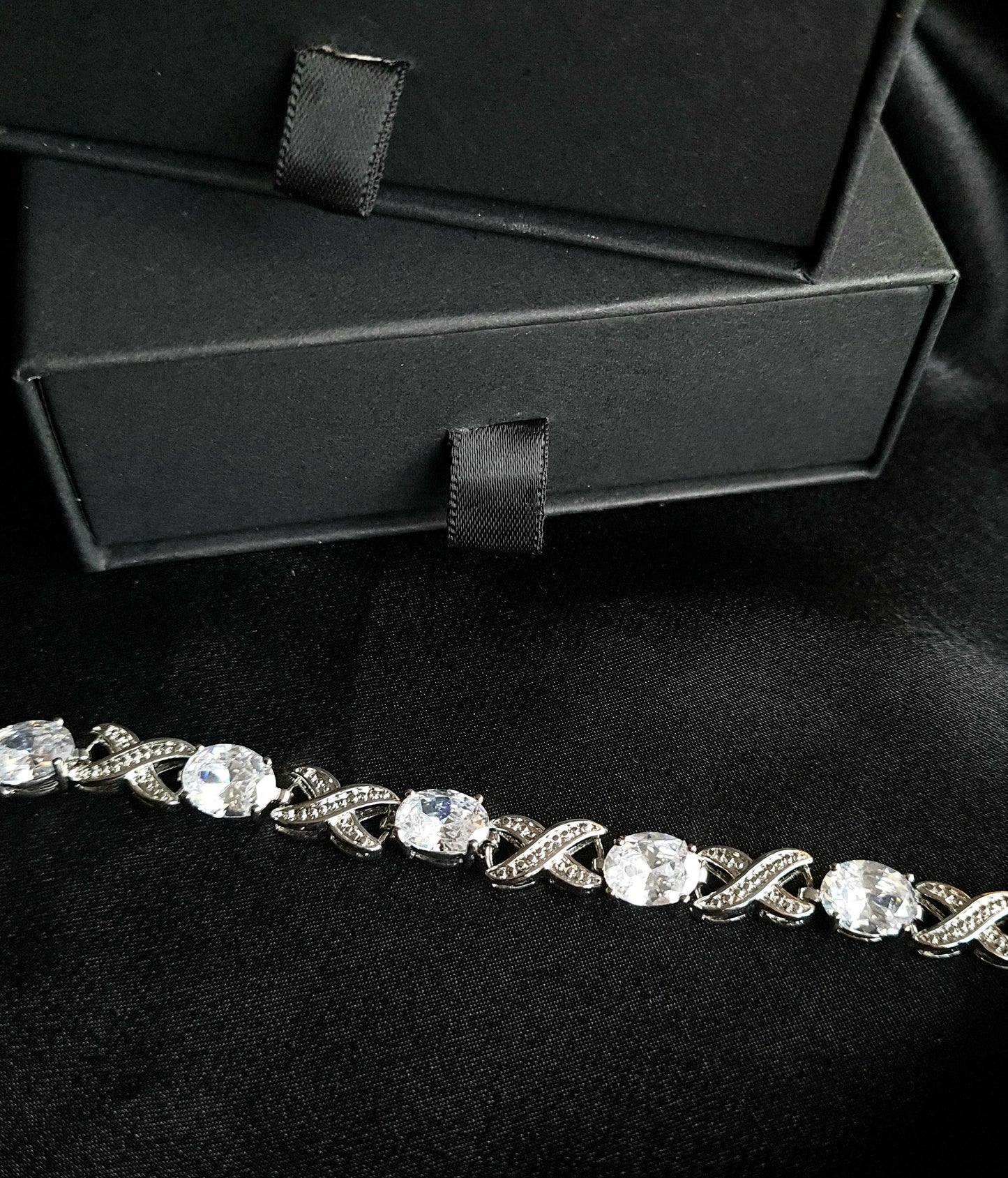 a close up look of a diamond bracelet  sparkling with Cubic Zirconia diamonds in a variety of shapes and sizes. displayed on a black fabric.