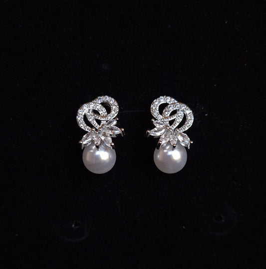 A pair of earrings with a pearl and rhinestones on a black background. The earrings are teardrop-shaped and have a simple, elegant design. The pearl is white and the rhinestones are clear.