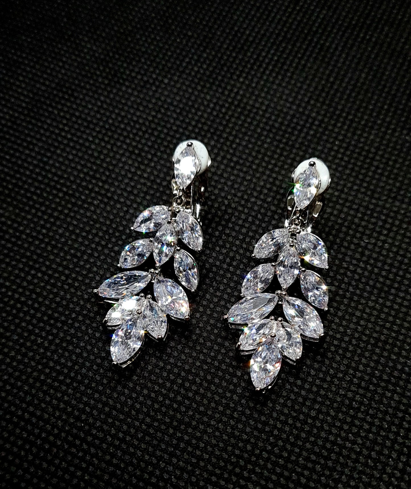 A pair of silver earrings with cubic zirconia. The earrings are simple in design and the cubic zirconia are sparkling. The earrings are a perfect accessory for a special occasion or a gift for a loved one.