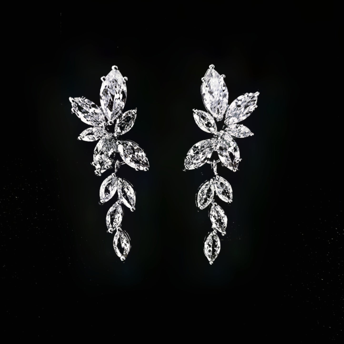 A close-up of a pair of silver earrings with white diamonds. The earrings are simple in design and the diamonds are sparkling. The earrings are very elegant and would be perfect for a special occasion.