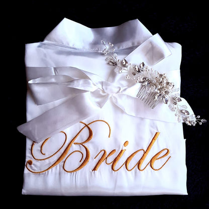 A white kimono with the word "bride" embroidered on it. The kimono is made of silk and has a simple design. The word "bride" is embroidered in gold thread and is located in the center of the kimono. The kimono is very elegant and would be perfect for a wedding.