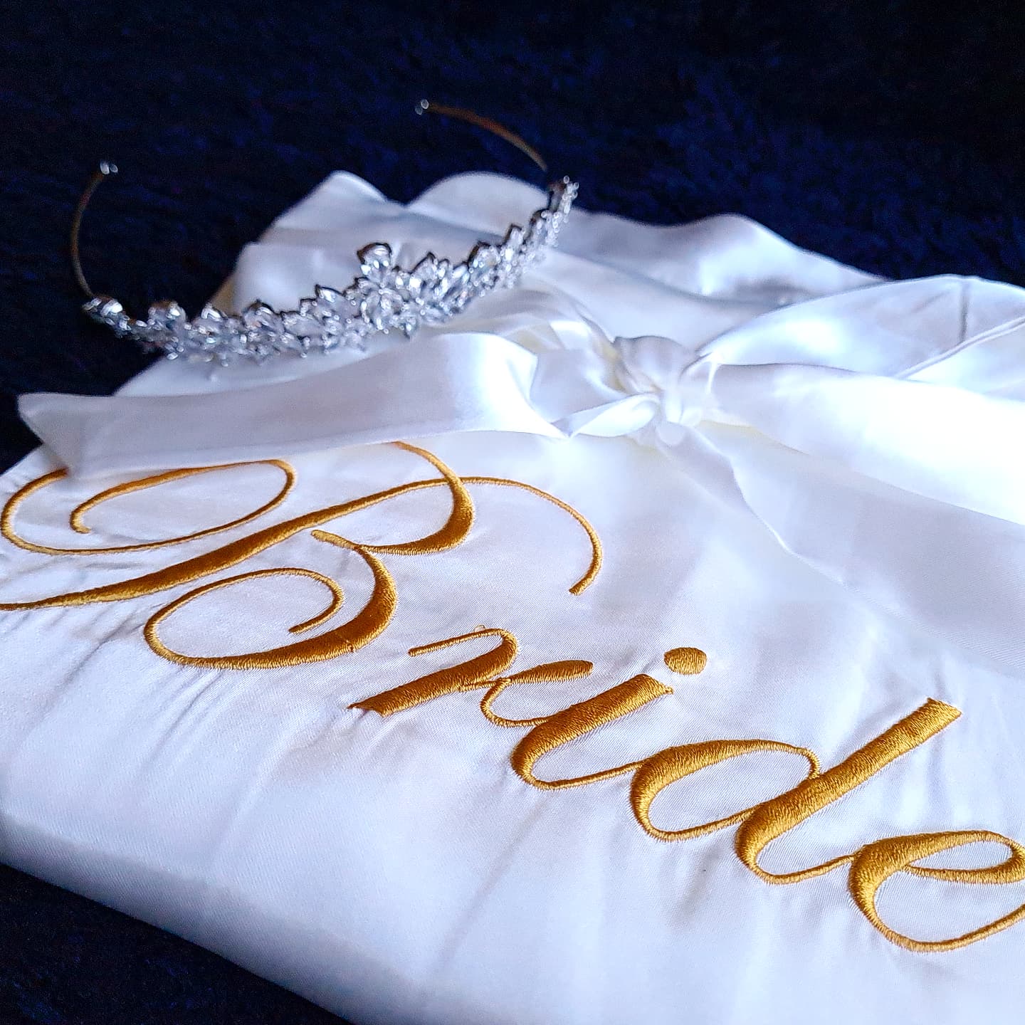 a side shot of A white kimono with the word "bride" embroidered on it. The kimono is made of silk and has a simple design. The word "bride" is embroidered in gold thread and is located in the center of the kimono. The kimono is very elegant and would be perfect for a wedding.