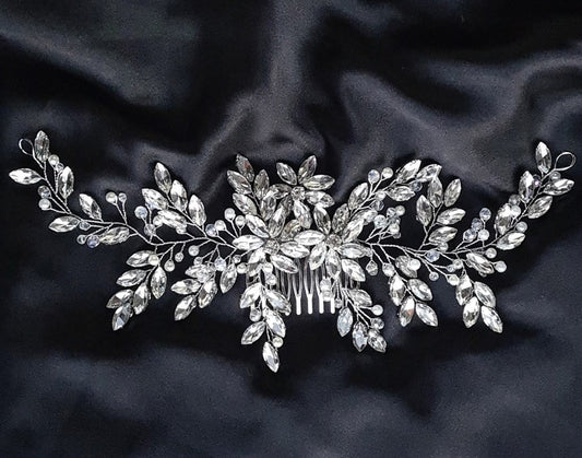 A hair comb with rhinestones and leaves on a black background. It has a delicate design with leaves and flowers. The rhinestones are clear and sparkling. The background is black.