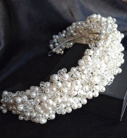 A wedding hair accessory made of pearls and crystals. The headband has a delicate design with pearls and crystals.