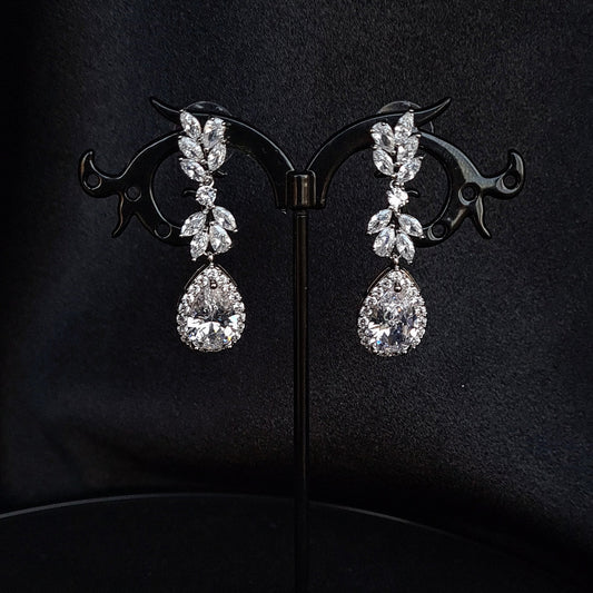 A pair of silver earrings with dangling teardrop pearls. The earrings are simple in design and the pearls are lustrous. The earrings are a perfect accessory for a special occasion or a gift for a loved one.
