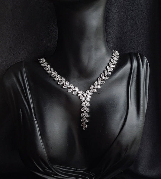 a necklace with cubic zirconia stones. The necklace is made of white silver and has cubic zirconia stones in a variety of shapes and sizes. The necklace is the main focus of the image and it sparkles in the light