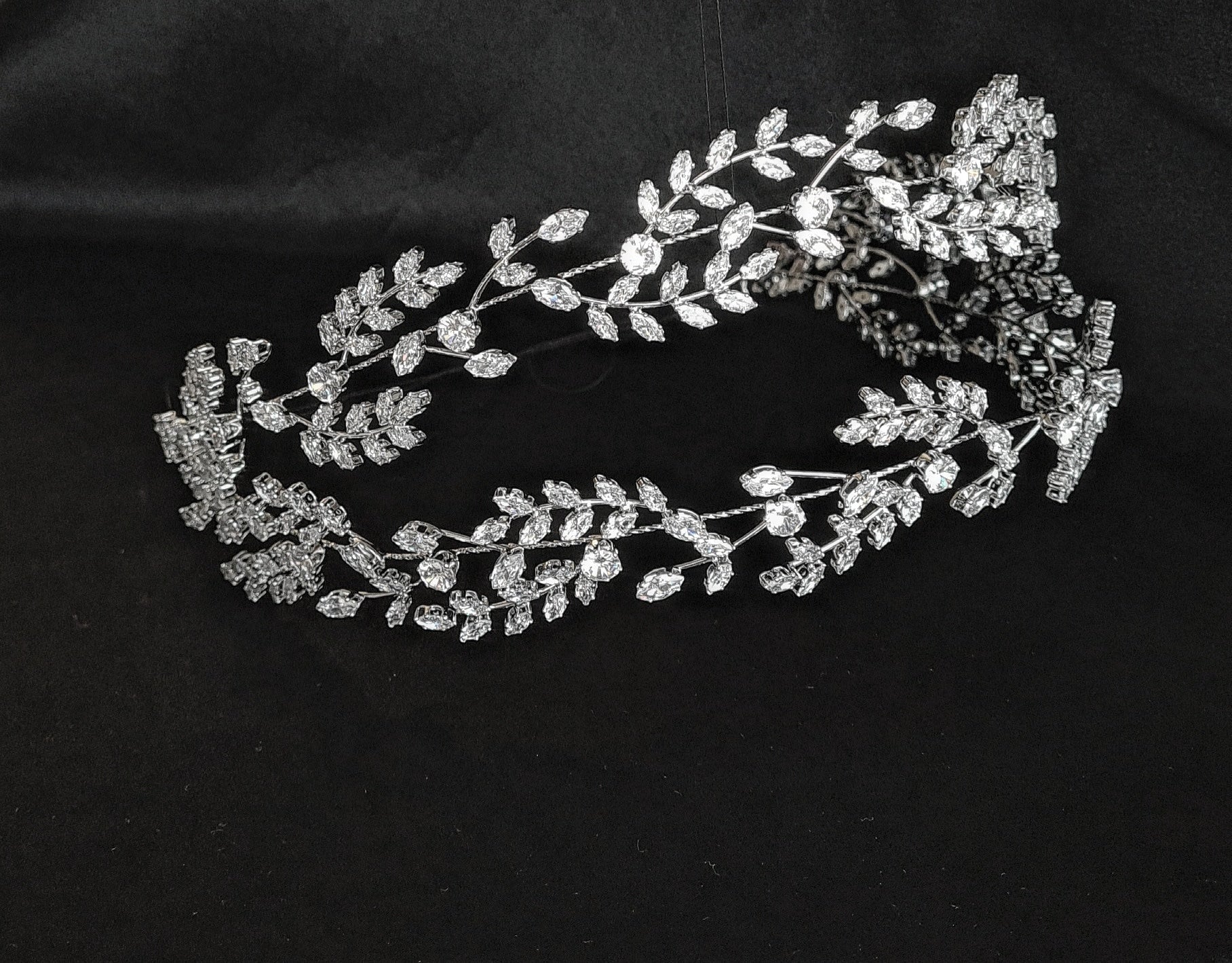 a bridal hairpiece with double rows of cubic zirconia on a black background. The hairpiece is made of cubic zirconia and has a delicate, feminine design. It is perfect for a bride who wants to add a touch of elegance to her wedding day look. The hairpiece is shown on a black background, so the cubic zirconia stands out beautifully