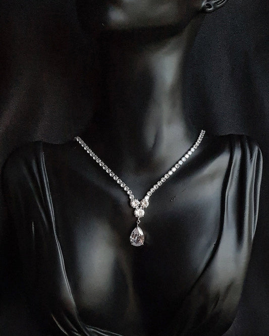Sparkling cubic zirconia teardrop necklace on mannequin. The necklace is made up of a single row of cubic zirconia stones in teardrop shape, which are sparkling and eye-catching. The necklace is perfect for a special occasion, such as a wedding or prom. It is also a great gift for a loved one.