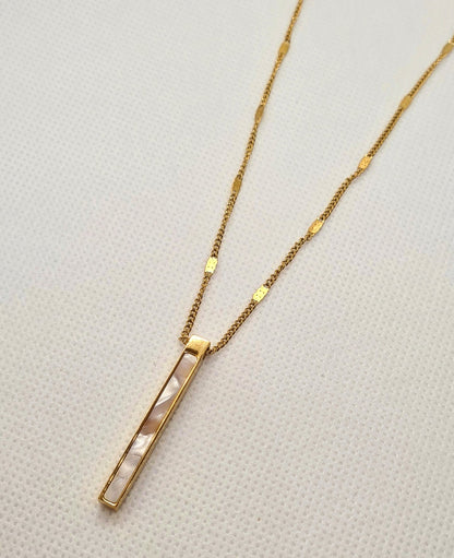Ayla Necklace a sleek and delicate golden chain with a long shell pendant.