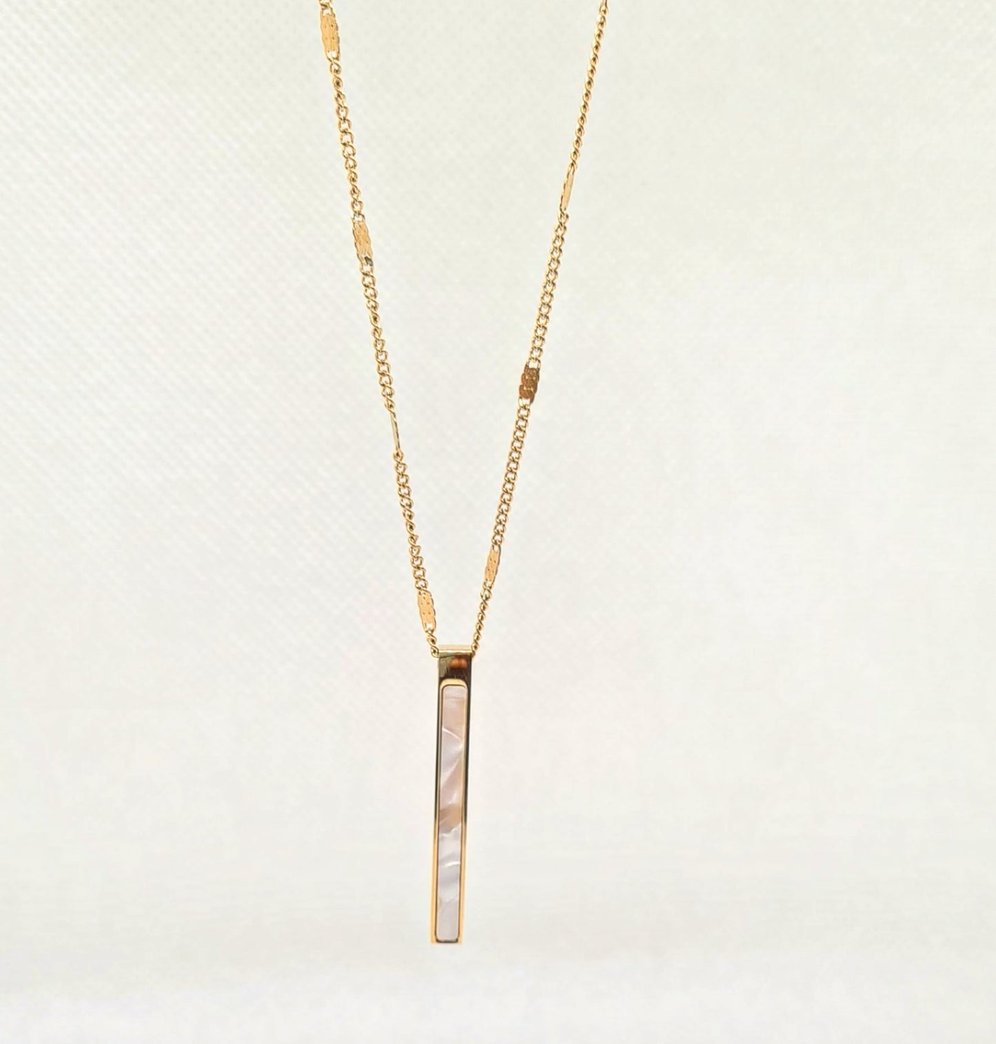 Ayla Necklace a sleek and delicate golden chain with a long shell pendant.