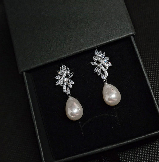 A pair of silver earrings with white pearls. The earrings are simple in design and the pearls are lustrous. The earrings are a perfect accessory for a special occasion or a gift for a loved one.