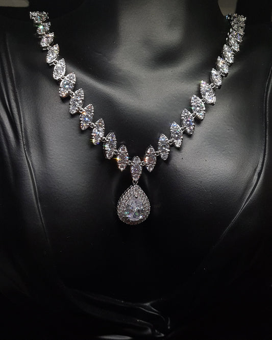 A mannequin wearing a diamond necklace with a large pendant. The necklace is made of silver and is set with a pear-shaped diamond. The pendant is surrounded by smaller diamonds. The necklace is elegant and sophisticated, and it would be a perfect addition to any formal outfit.
