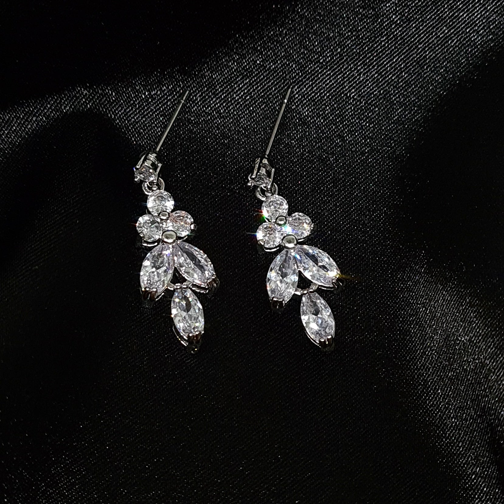 A close-up of a pair of silver earrings with cubic zirconia. The earrings are simple in design, with a modern twist. The cubic zirconia are sparkling and the earrings are a perfect accessory for a special occasion or a gift for a loved one.
