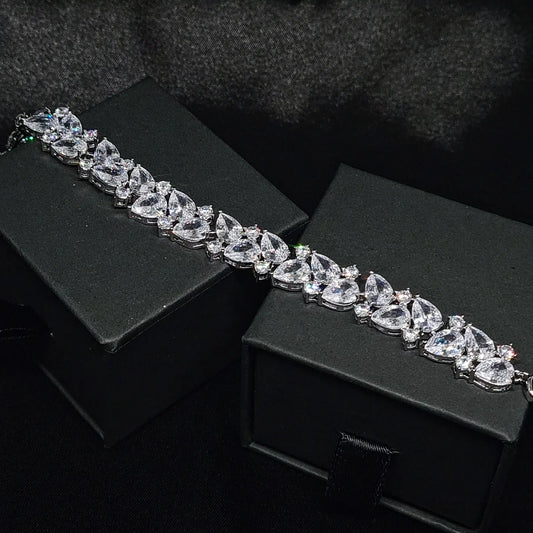 A close-up of a silver bracelet with diamonds on a black background. The bracelet has a intricate design with a double row of diamonds. The diamonds are sparkling and the bracelet is very shiny.